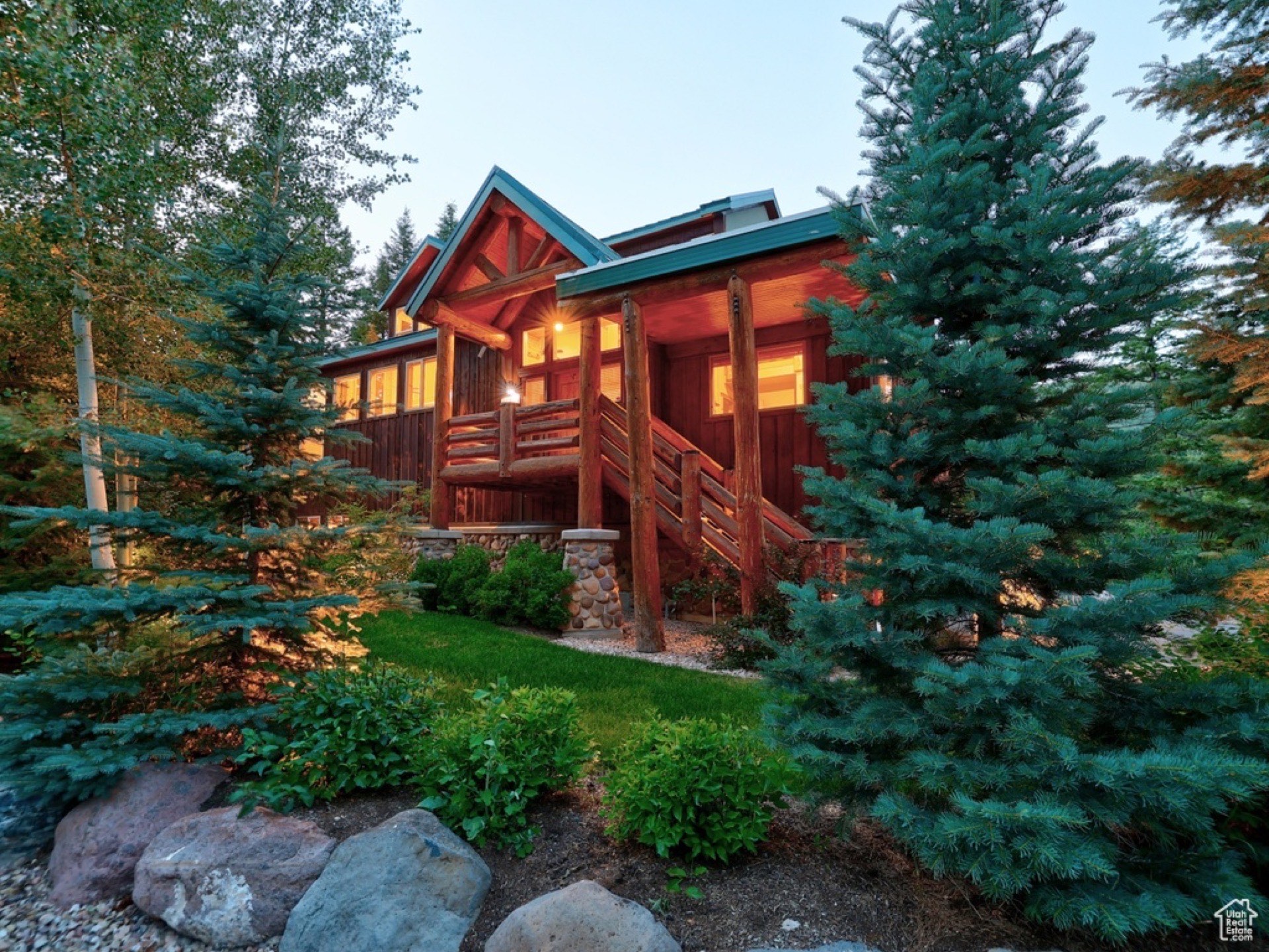 Timp Haus cabin exterior at dusk with glowing windows, surrounded by pine forest